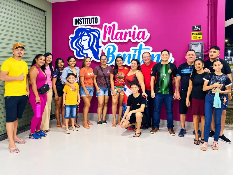 Crianças e adultos reunidos diante do logo do Instituto à noite